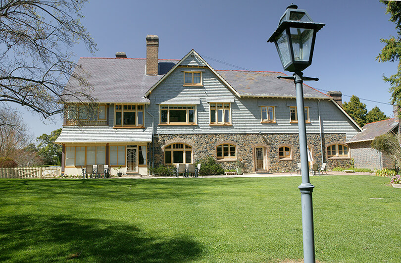 Western elevation of shingled homestead showing large lawn area and old fashioned lamp post 