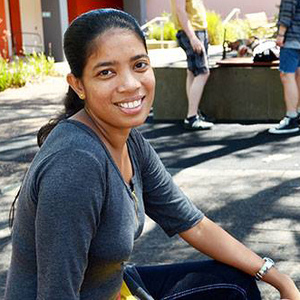 UNE graduate smiles in UNE campus courtyard