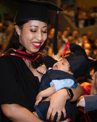 Image of student at graduation holding a baby