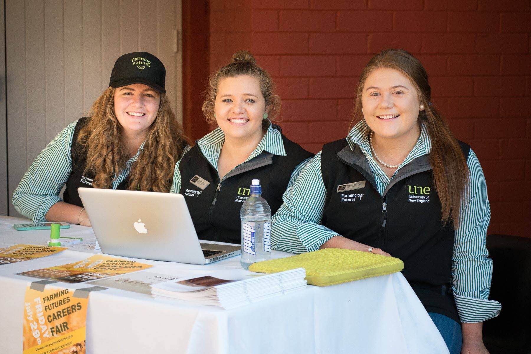 Three female students sit at computer in farming futures uniform collecting registrations