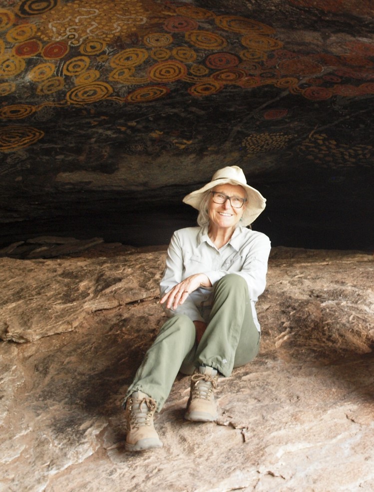 A woman wearing glasses and a wide-brimmed hat sitting in a cave.