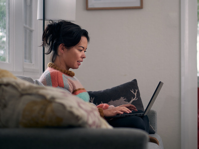 UNE student studies on a laptop on her lounge at home
