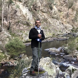 Bachelor of Arts Archaeology student Colin Ahoy on a rock beside a local river