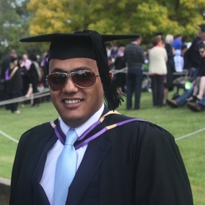 UNE graduate on campus in graduation cap and gown