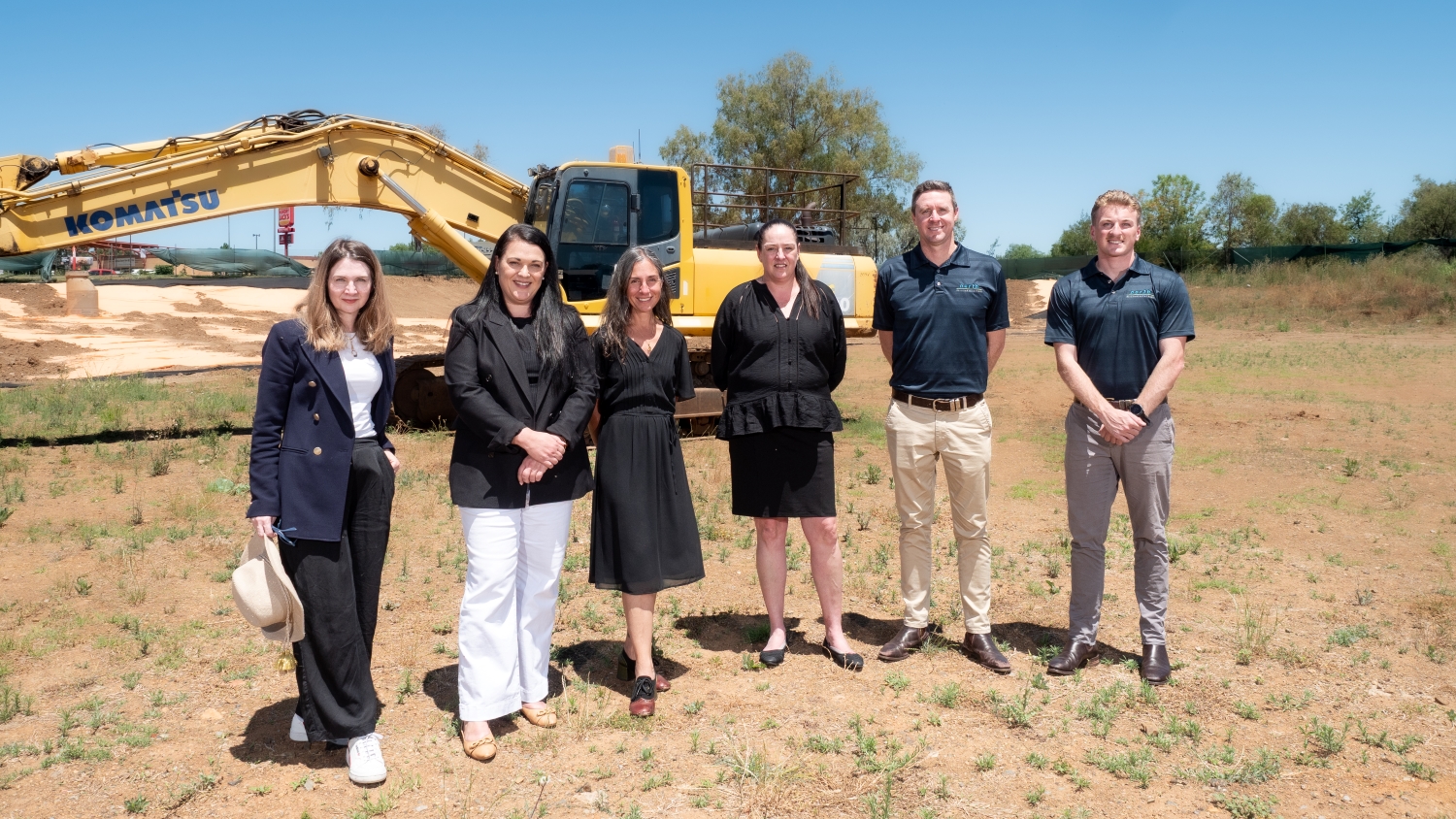 UNE staff and builders stand in front of a digger on site