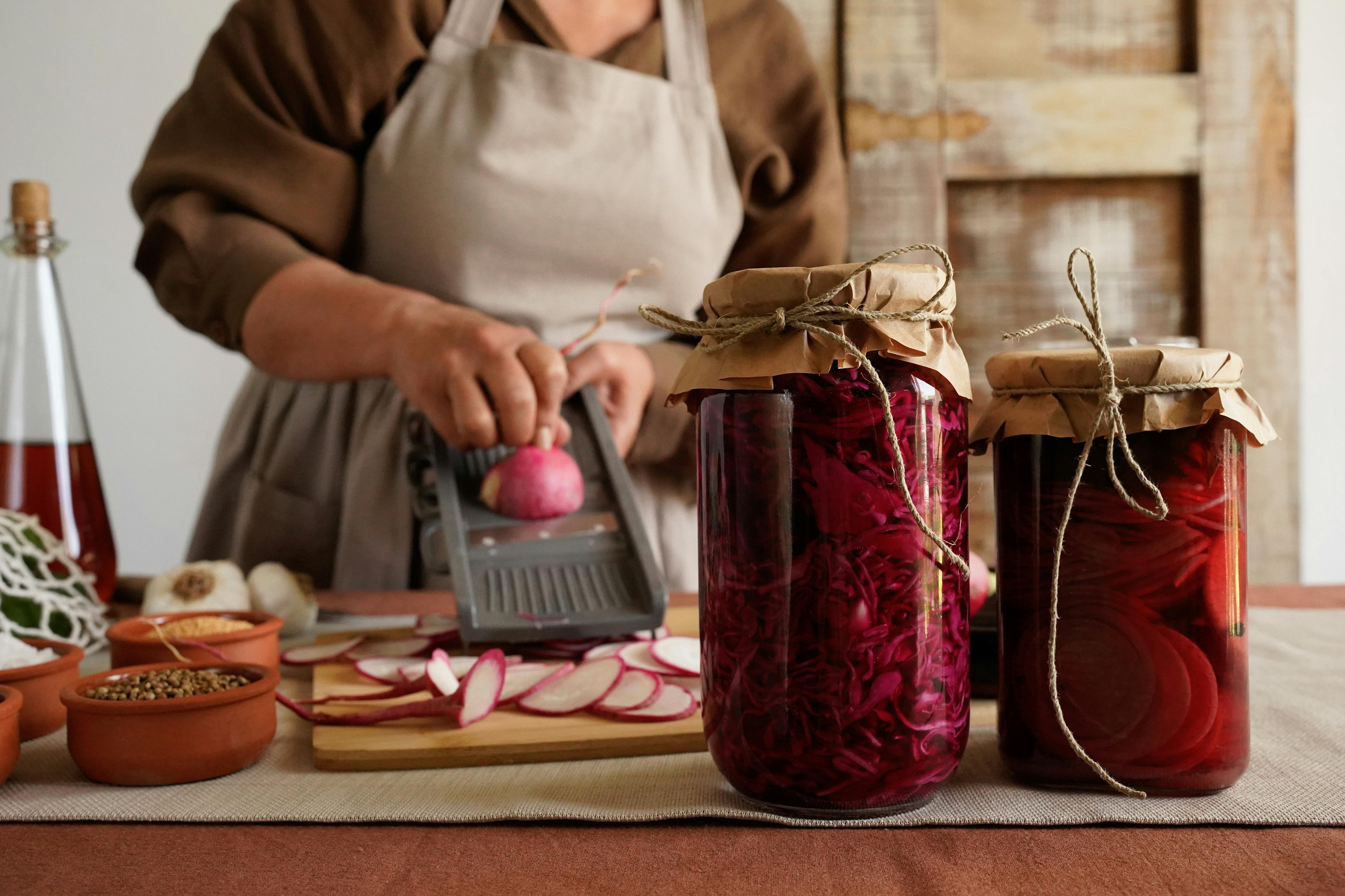 Someone preparing jars of fermented vegetables
