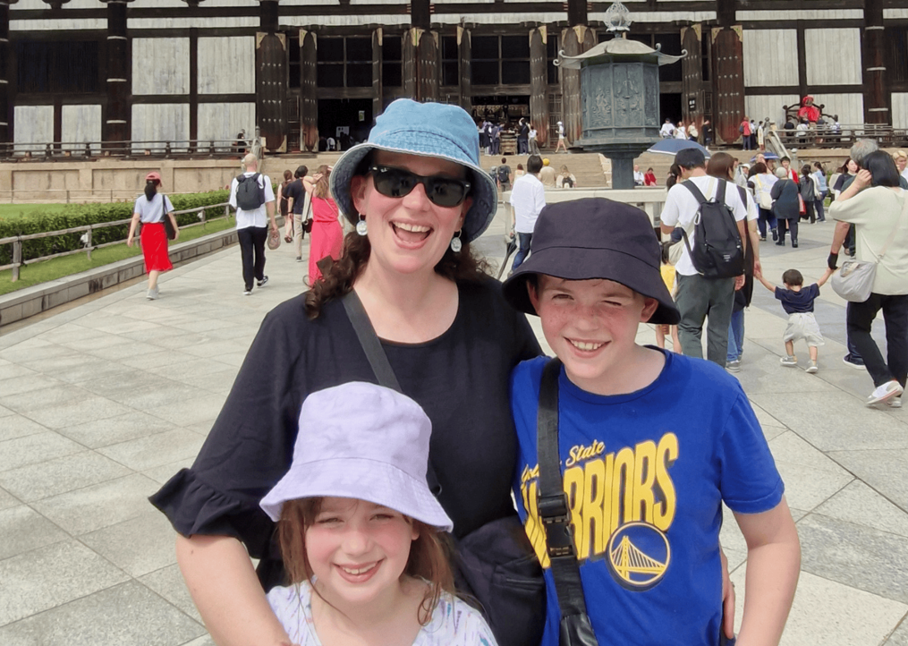 Travel photo of Nicole and smiling children on the steps of a shrine in Nara, Japan. 