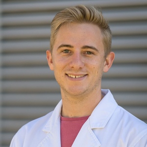 UNE PhD and Bachelor of Science (Hons) graduate Matthew Hilliar smiles in white lab coat