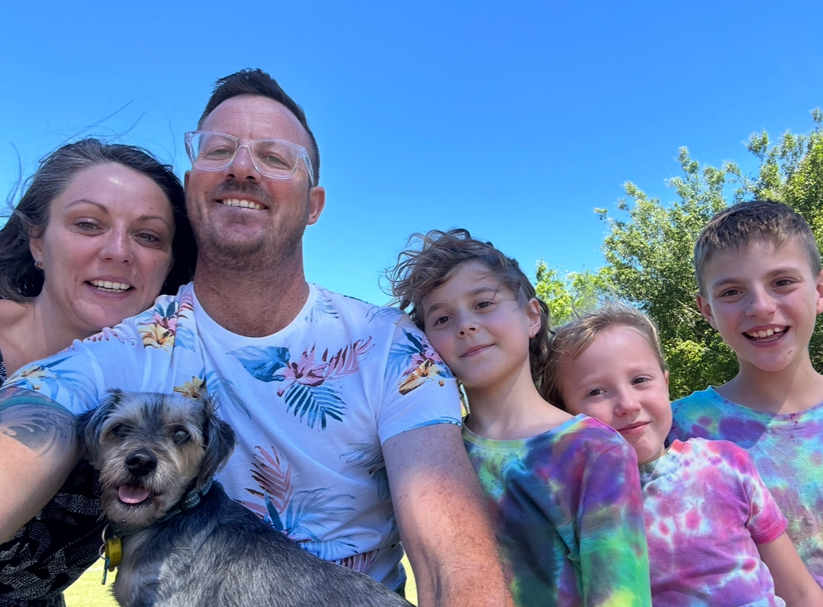 Family photo of a mum and dad with their three children and family dog. 