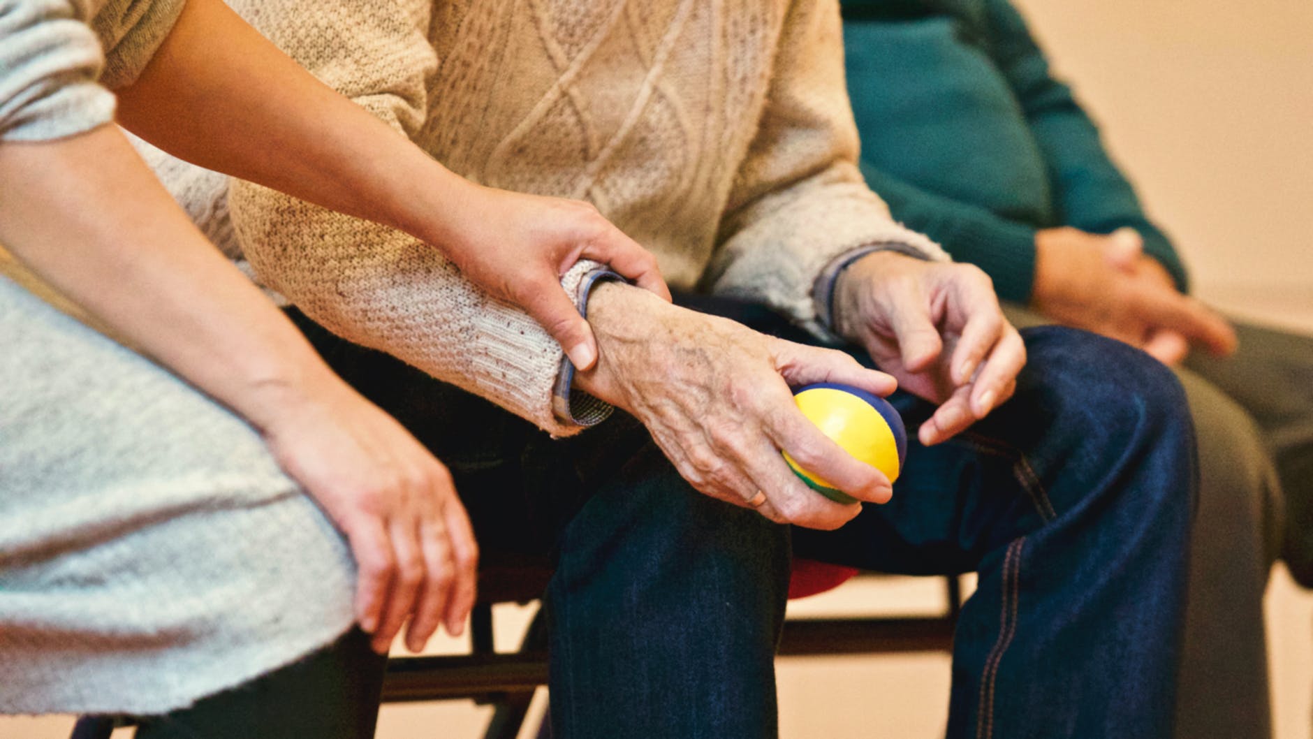 Close-up of the hands and arms of an older person and younger person sitting together