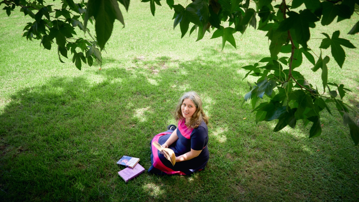 Lisa Hackett reading romance novels under a tree.