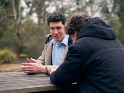 UNE student on park bench discusses studies with a peer