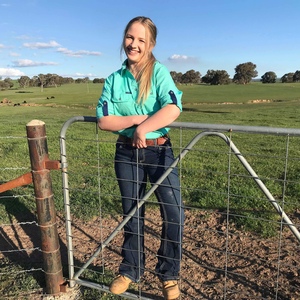 UNE Bachelor of Rural Science graduate Sara Paton leans over gate on a sunny day on a rural property
