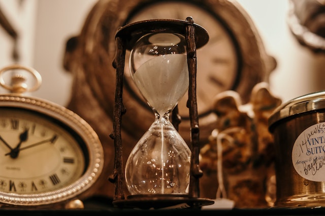 Sand timer surrounded by antique clocks