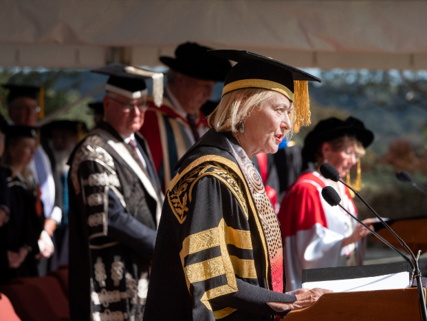Dr Sarah Pearson wears official robes and speaks at a UNE graduation ceremony