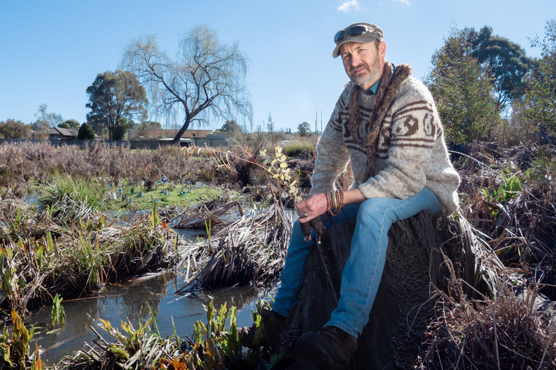 Marty Branagan in a natural landscape beside a waterway. 