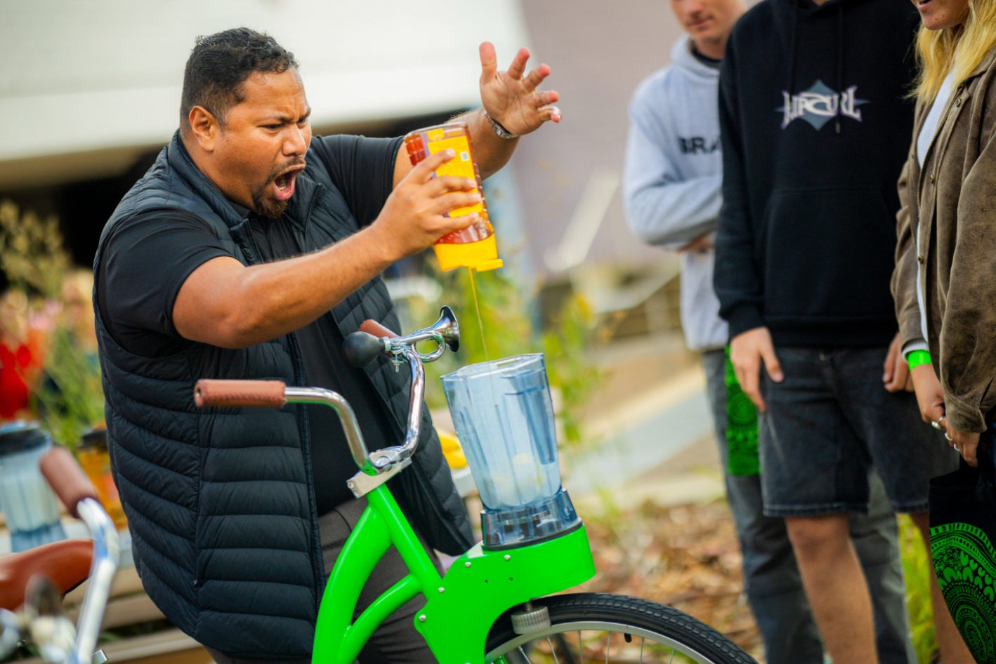 UNE Staff excitedly pouring honey into smoothie bikes for attendees 