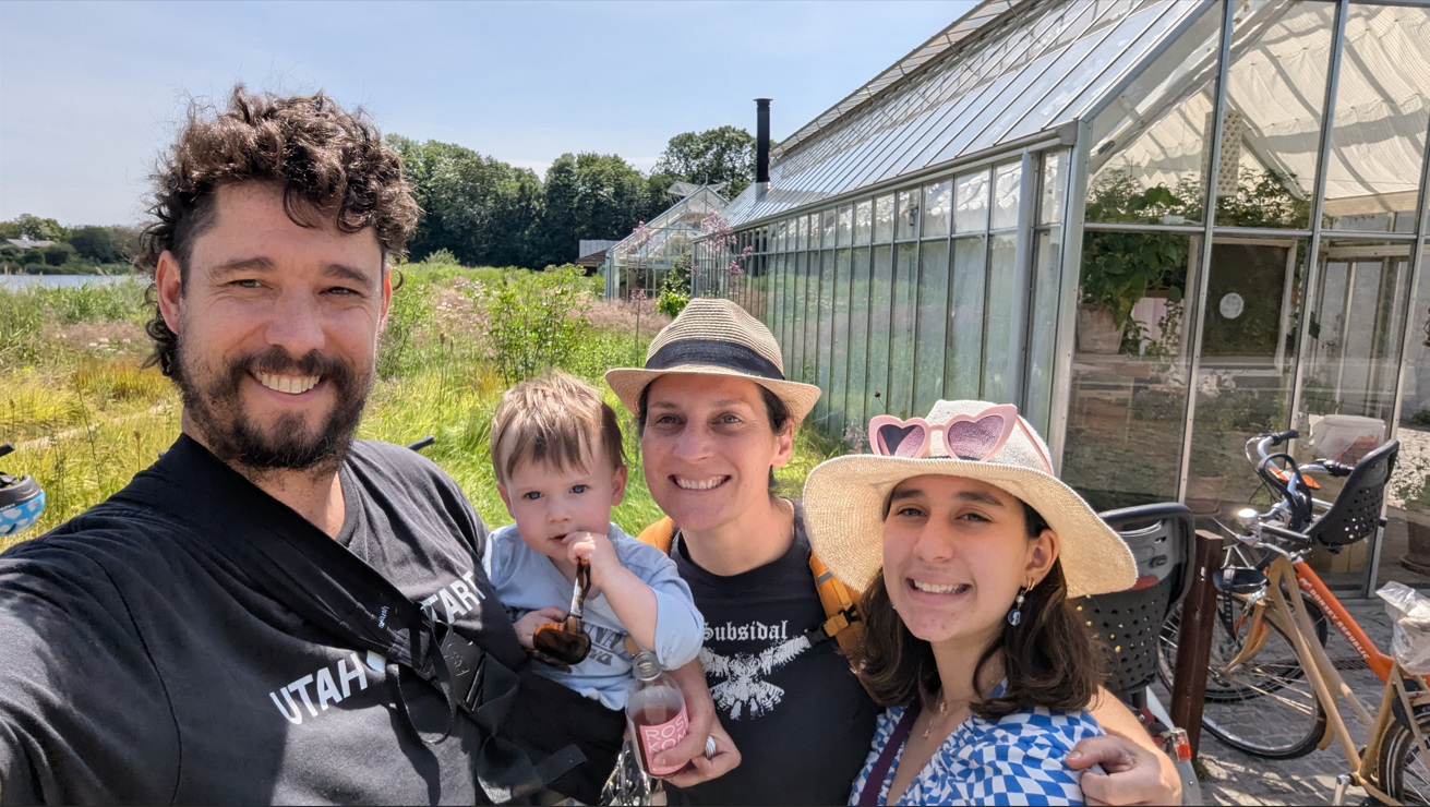 A casual family portrait of UNE Urban and Regional Planning student Jac Torres Gomez with her family - partner Adam holding two-year-old Louie and alongside 14-year-old daughter Bella