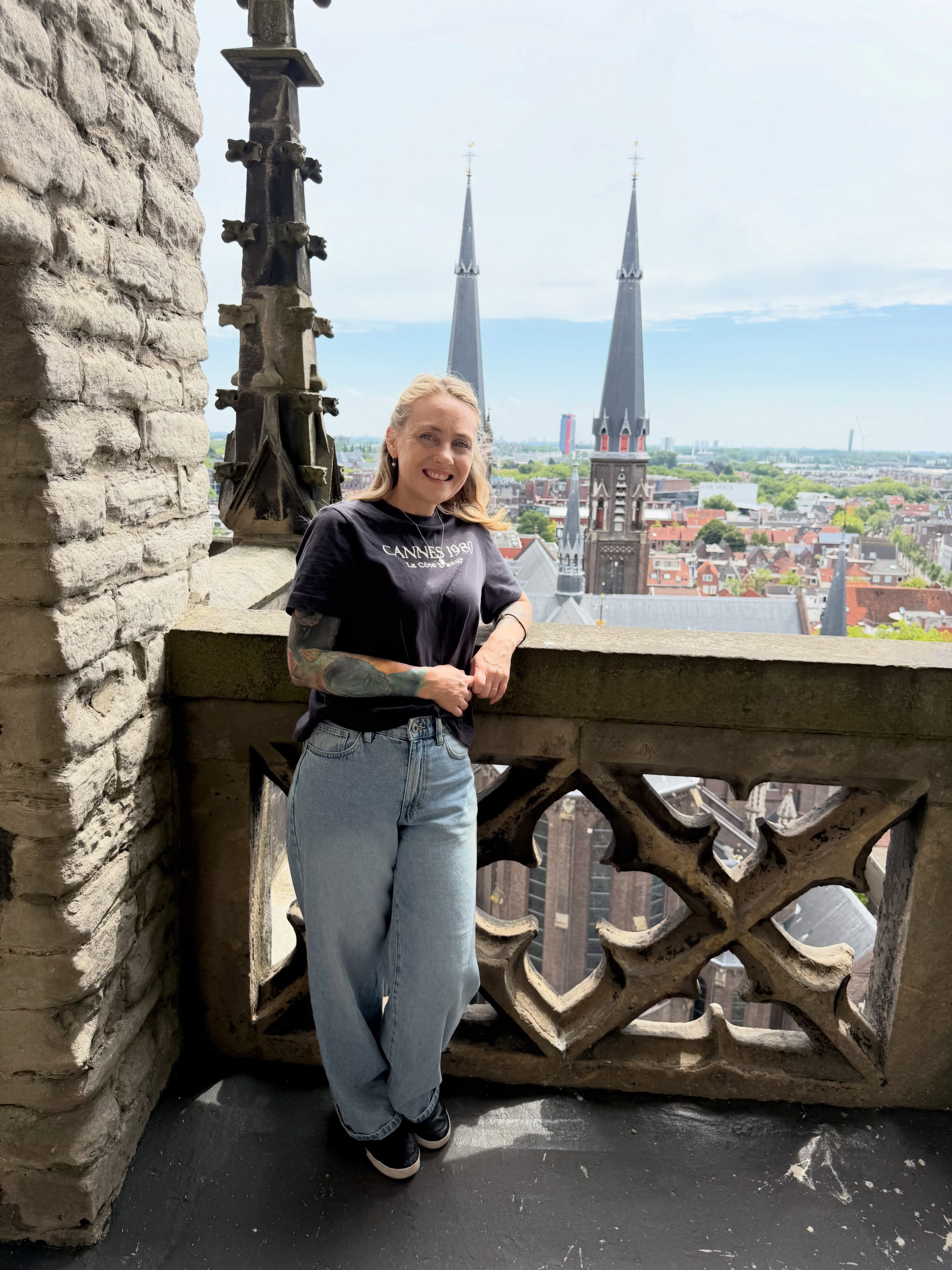 Rebecca stands on a gothic-style balcony overlooking other medieval-style buildings in the Netherlands