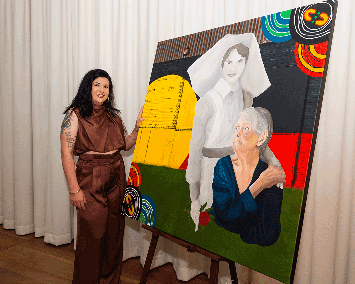 Aboriginal woman artist standing next to her painting on a large canvas