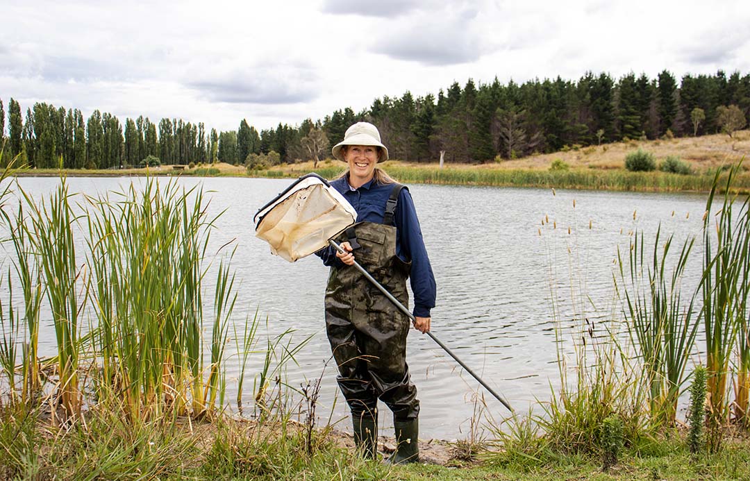 Lindsey Frost holding a net in front of UNE's Lake Zot
