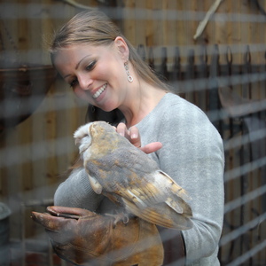UNE graduate Kat Stewart strokes an owl sitting on her arm