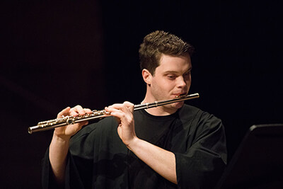 Male student dressed in black playing flute