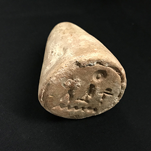 Small cone-shaped stamp with primitive people-like impressions