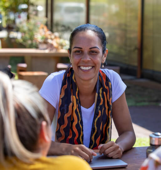 A smiling women talking to a group of children. 