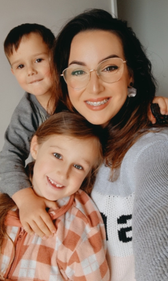 Mother with glasses takes a selfie with her son and daughter.