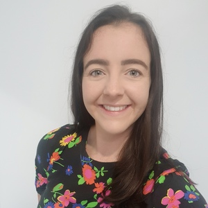 UNE Diploma in Modern Languages graduate Olivia Bounds smiles for camera in a colourful floral shirt