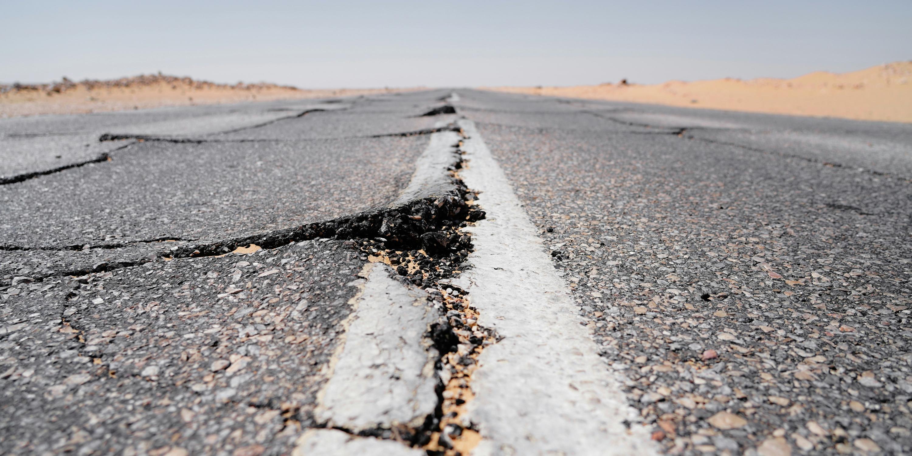 Image shows large cracks forming in the middle of a road.