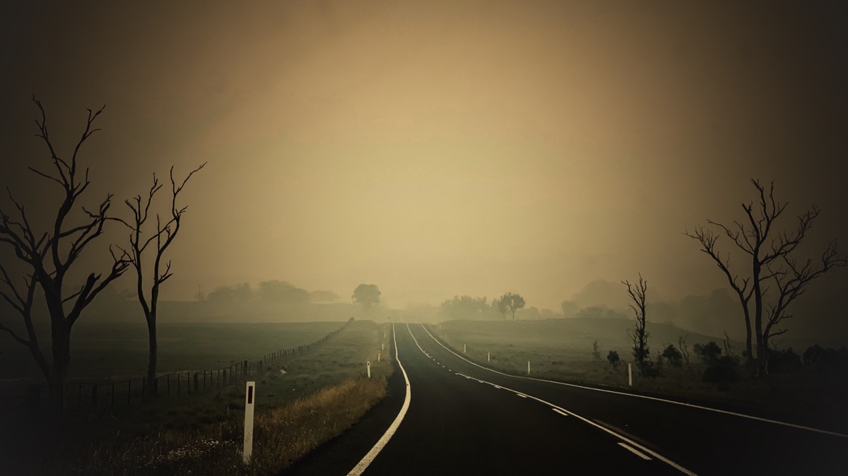 Moody image of a country road disappearing into dense bushfire smoke