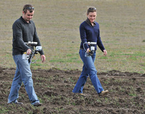 Two people inspecting ploughed ground.