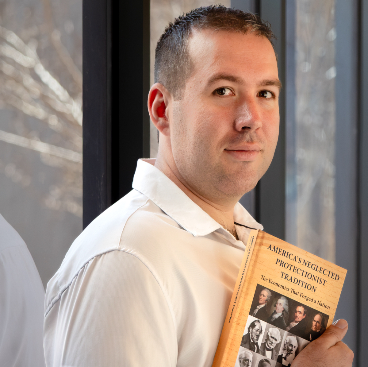 man holding book looks at camera