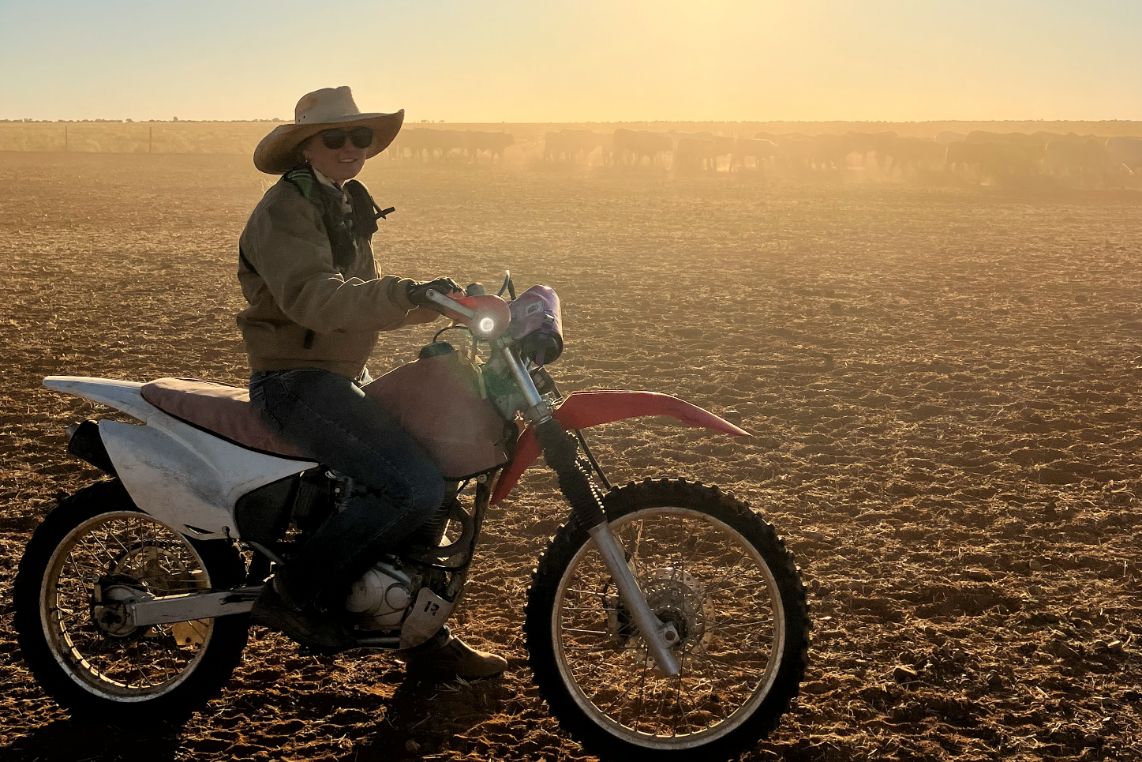 Katie Marsden on a motorbike with cattle in the distance