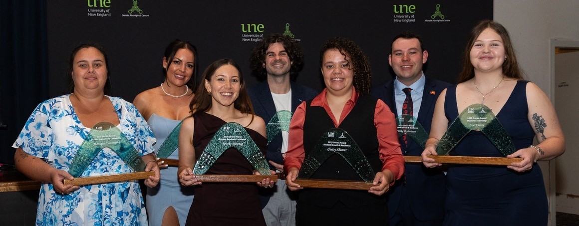 seven people holding glass boomerang awards 