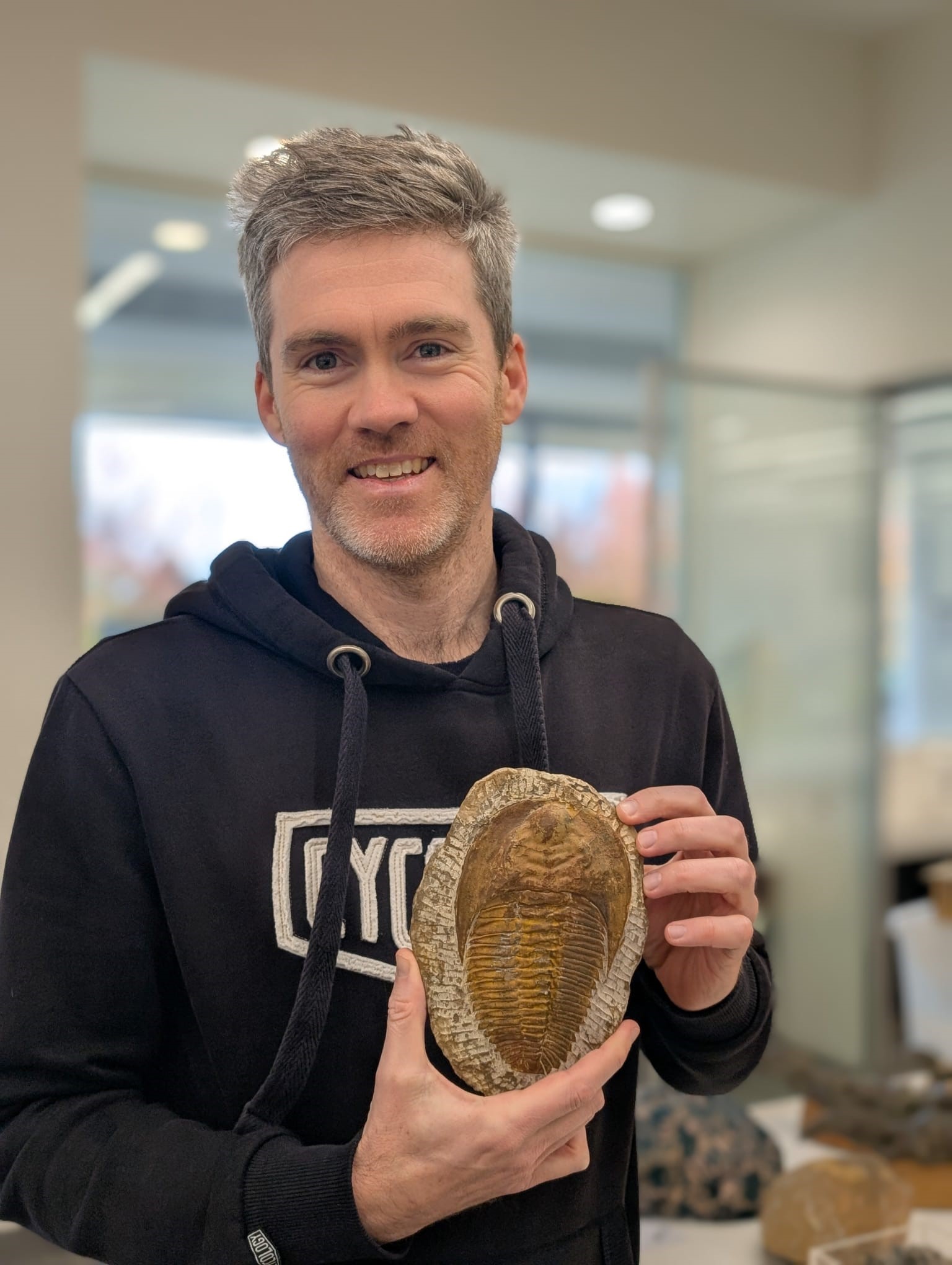 Dr James Holmes holding a trilobite fossil