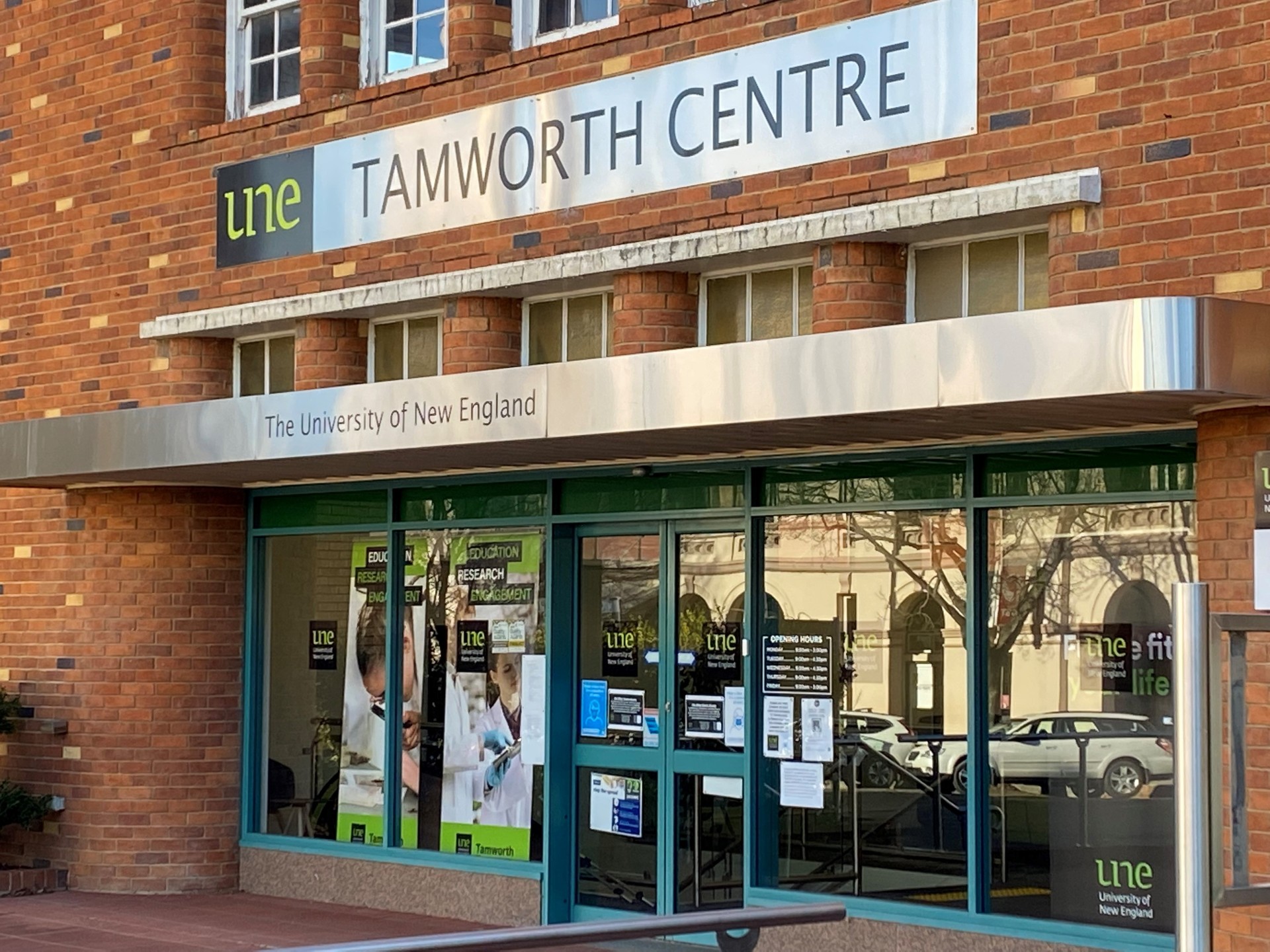 An image of a red brick building that says UNE Tamworth 