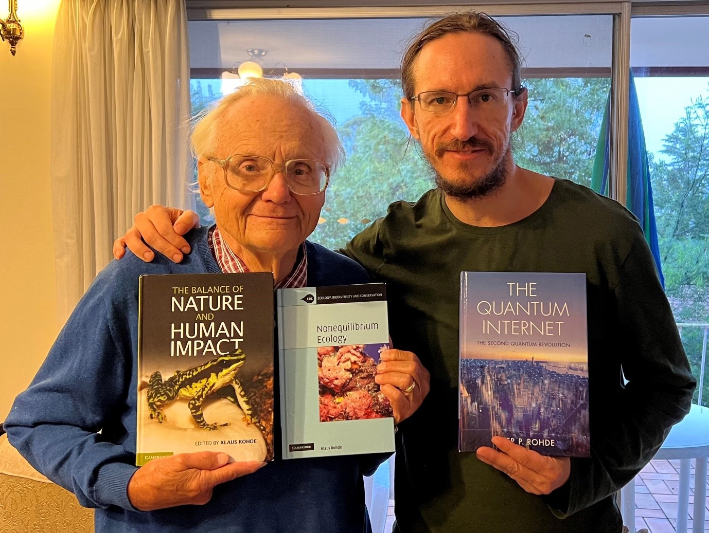 Klaus and Peter Rohde holding three of his books.