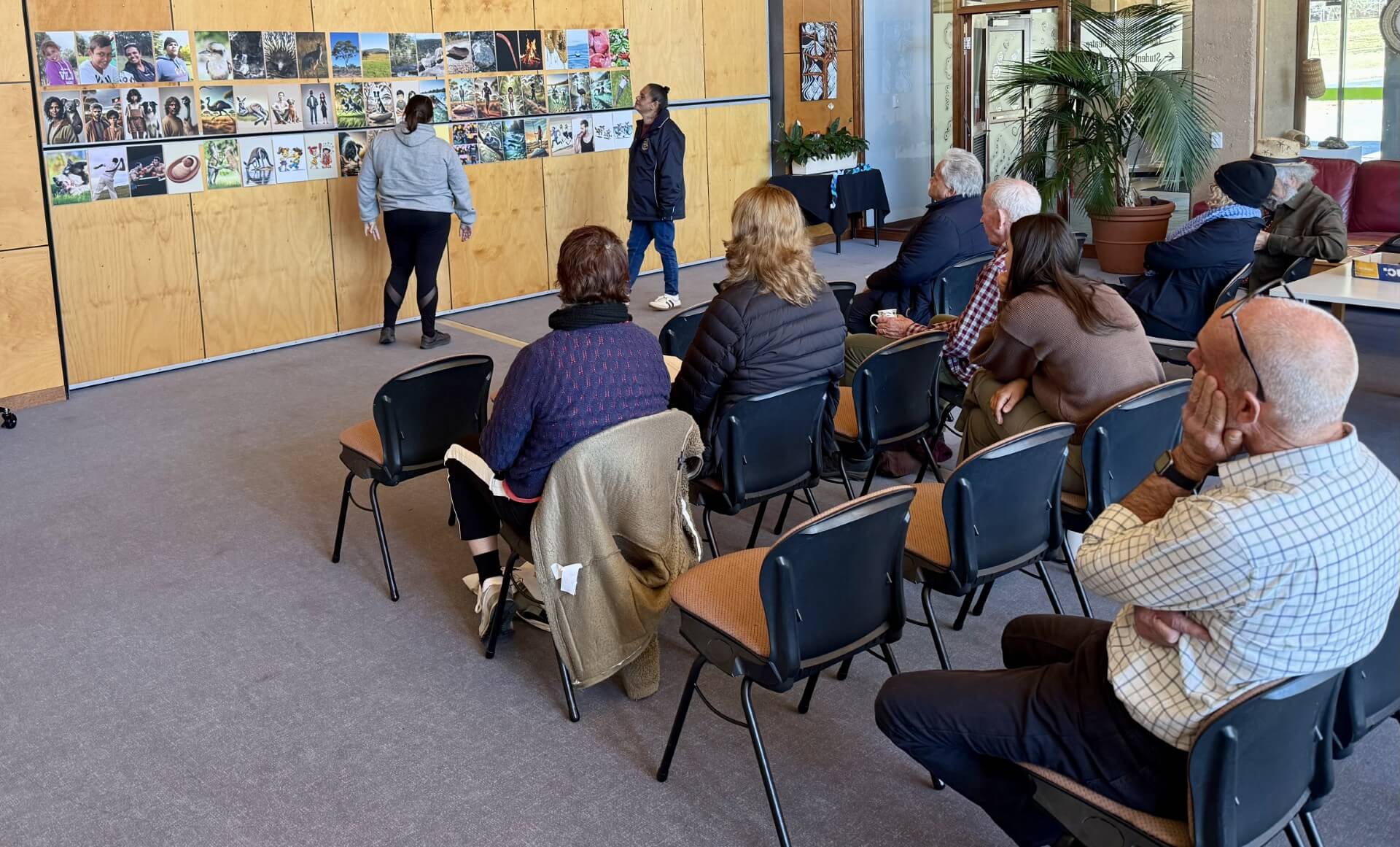 Seated people learning from two presenters.