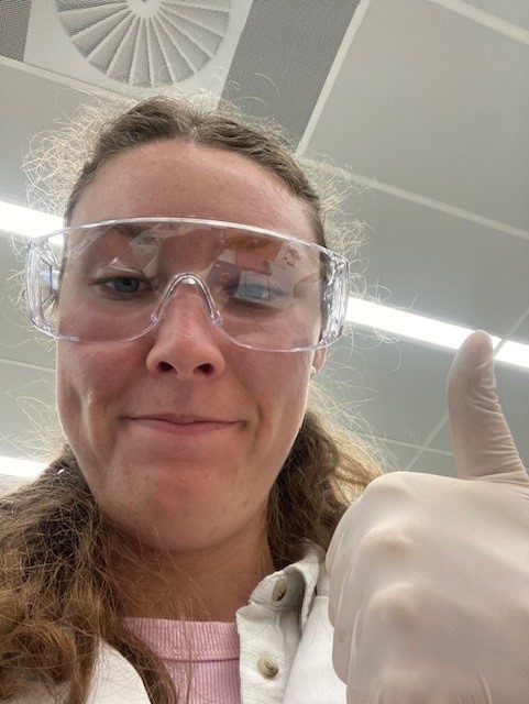 Amelia in the lab Amelia Wearing wearing safety goggles and a lab coat.