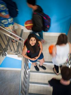 Female student standing in stair well as other students move past her