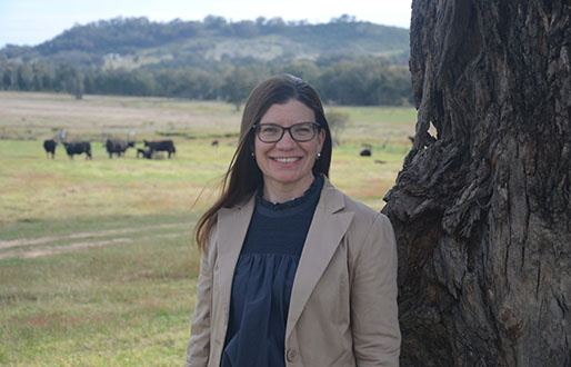 Maria Thompson smiling at the camera with a green paddock in the background.