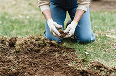 A farmer collects a clod of earth and grass