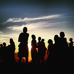 Group of young people silhouetted against a sunset  