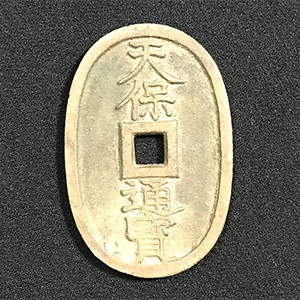 Ancient oval coin with central square cutout and Japanese characters 