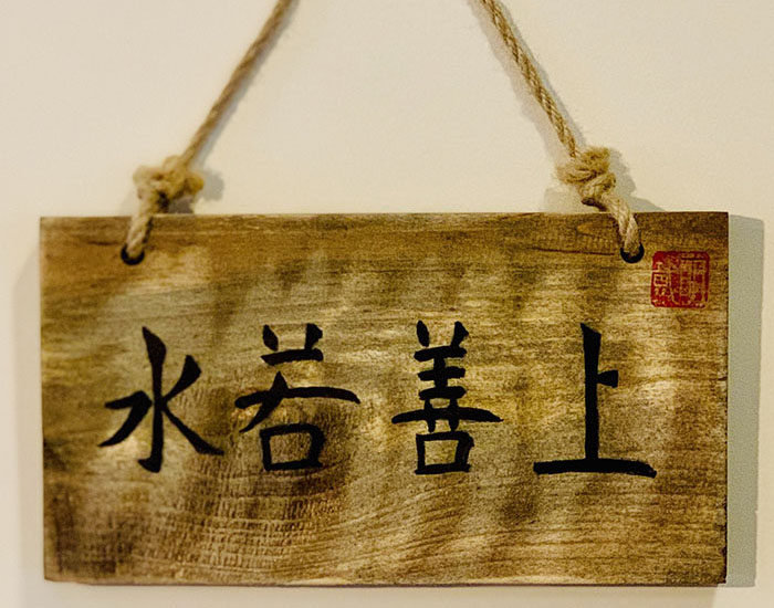 Artwork featuring a hanging wooden board with Chinese characters