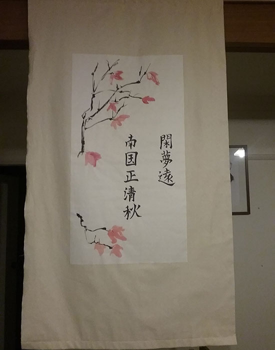Neutral coloured and traditional-looking paper scroll featuring water colour pink cherry blossoms and Chinese characters