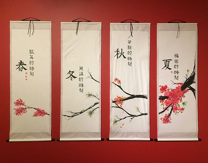 A watercolour cherry blossom branch crosses three silk-like hanging banners with Chinese characters